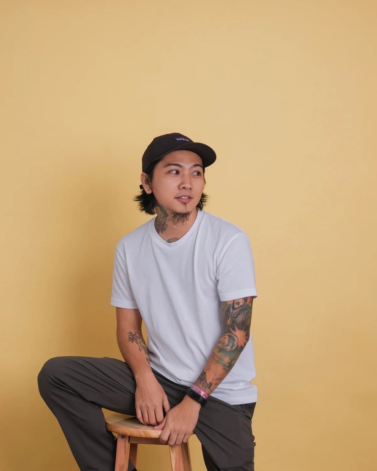 Eroll Encabo, founder of Beyond Vision Digital, sitting on a stool against a warm yellow backdrop.